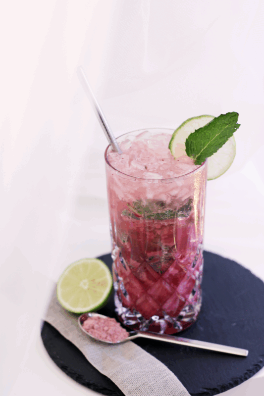 Schalquito Mocktail mit STRAWBERRY STAR Bio Vegan Protein Pulver in einem Kristallglas mit Crushed Ice, frischer Minze und Limettenscheibe auf einer schwarzen Schieferplatte.
