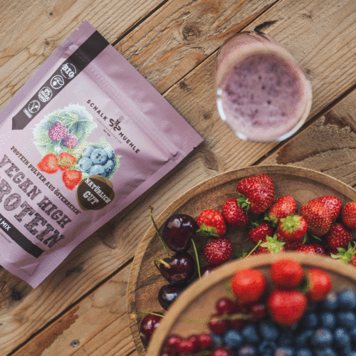 Bild zeigt Schalk Mühle Beeren Protein mit einem Glas geshaktem Protein und einem dekorativen 2-stöckigem Beeren Teller
